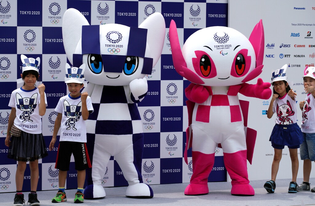 FILE - In this July 22, 2018, file photo, Tokyo 2020 Olympic mascot "Miraitowa", left, and Paralympic mascot "Someity", right, pose with children for photographers during the mascot debut event in Tokyo. The countdown is on for the 2020 Tokyo Olympics. Tuesday, July 24, marked two years to go until the opening ceremony will be held at the brand new National Stadium in central Tokyo.(AP Photo/Eugene Hoshiko, File)