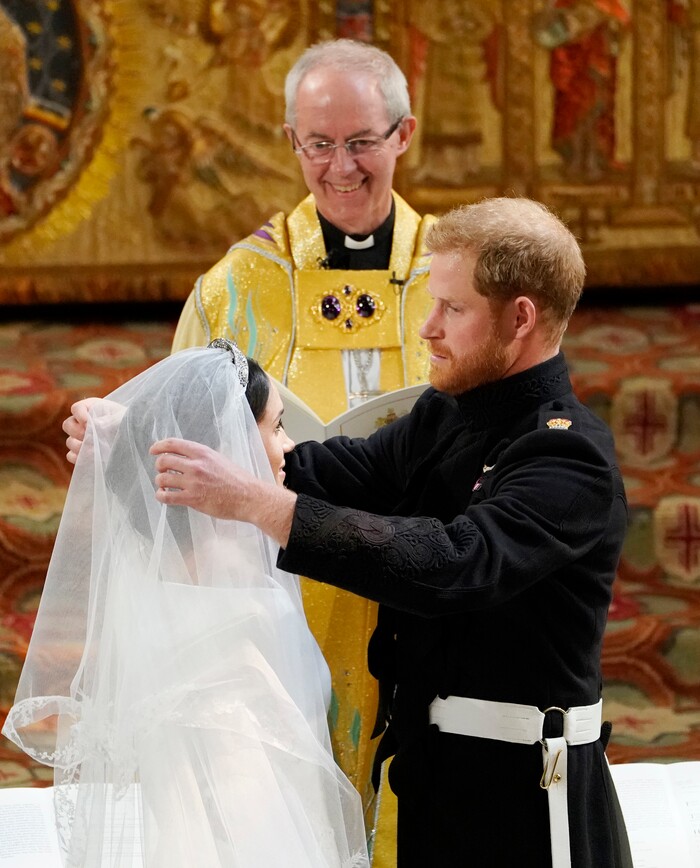 Britain's Prince Harry pulls back the veil of Meghan Markle watched by Archbishop of Canterbury Justin Welby during their wedding at St. George's Chapel in Windsor Castle in Windsor, near London, England, Saturday, May 19, 2018. (Owen Humphreys/pool photo via AP)