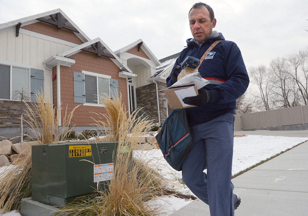 (Al Hartmann  |  The Salt Lake Tribune) Postal carrier Ben Frost delivers mail and packages on his regular route in Murray Thursday, Dec. 22, 2016.