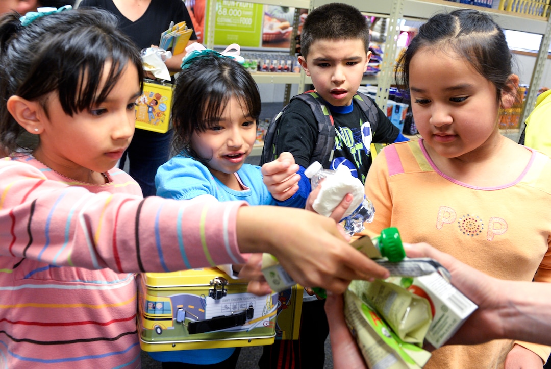 (Leah Hogsten  |  The Salt Lake Tribune) l-r Siblings Diana Escobar, Elizabeth Escobar, Jonathan Escobar and friend Fernanda Hernandez stuff their new lunch boxes with food to fill their school's food pantry, Tuesday, March 13, 2018 after the pantry dedication at their school. Smiths Food & Drug is helping to open a food pantry at David Gourley Elementary School in Kearns, where 80 percent of the 646 students qualify for free or reduced lunches. 