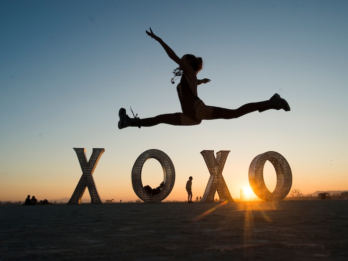 (Rick Egan  |  The Salt Lake Tribune)Frida Ahlvarsen does a leap in front of the XOXO installation by Laura Kimpton and Jeff Shomberg, at sunrise, during Burning Man 2017, Saturday, September 2, 2017.