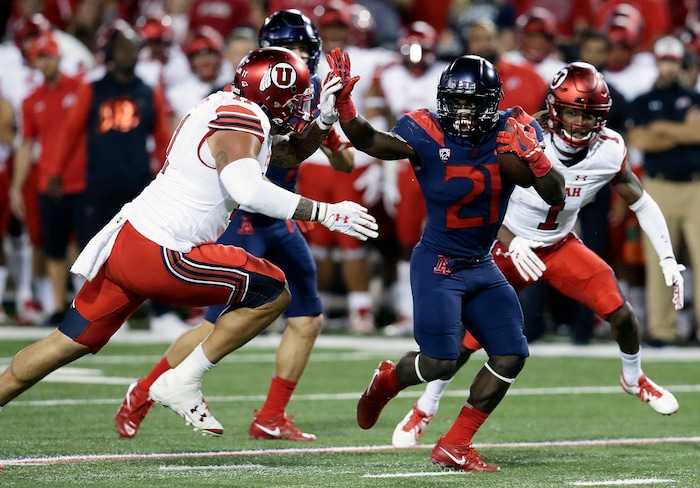 Arizona running back J.J. Taylor (21) tries to fend off Utah defensive end Kylie Fitts during the first half of an NCAA college football game, Friday, Sept. 22, 2017, in Tucson, Ariz. (AP Photo/Rick Scuteri)