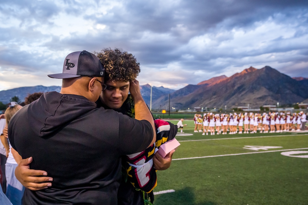 (Trent Nelson  |  The Salt Lake Tribune) Lone Peak's Bott Mulitalo II embraces members of the coaching staff as Lone Peak hosts Lehi, high school football in Highland on Thursday, Oct. 9, 2025.