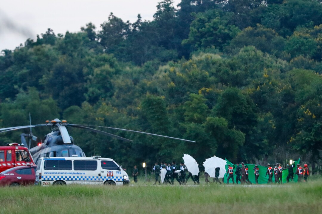 An emergency team rushes to a helicopter believed to be carrying one of the rescued boys from the flooded cave in Mae Sai as divers continue to extract some of the 12 boys and their coach trapped at Tham Luang cave in the Mae Sai district of Chiang Rai province, northern Thailand, Tuesday, July 10, 2018. Thai Navy SEALs say all 12 boys and their coach were rescued from the cave, ending an ordeal that lasted more than 2 weeks. (AP Photo/Vincent Thian)