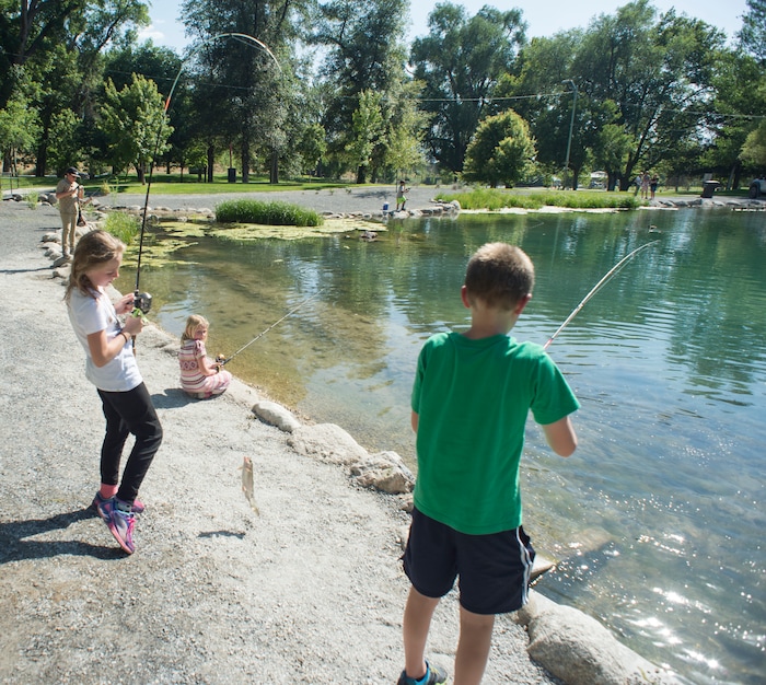 (Rick Egan  |  The Salt Lake Tribune)        Mira Peterson 11, reels in a fish at Fairmont Park Pond, during the grand reopening celebration, Wednesday, June 27, 2018.