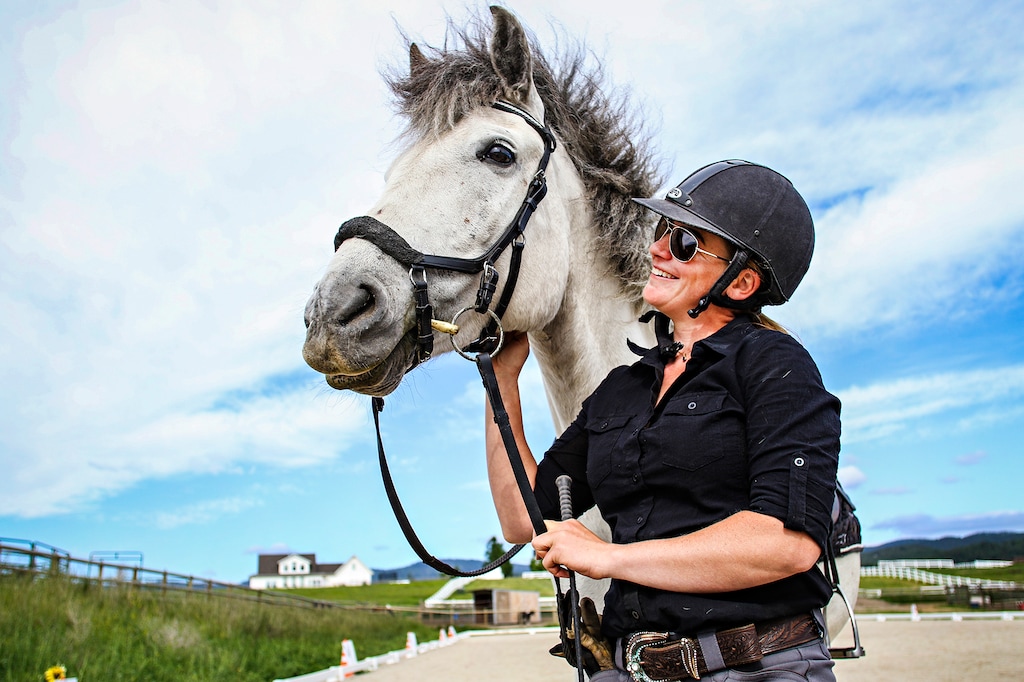 In a June 19, 2019 photo, Danica Yates, a dressage instructor and member of the Freedom Horse Farm, pets her horse Crystal in the Triple Take Arena west of Kalispell, Mont. Chrystal is one of several horses Yates has rescued throughout her years as a trainer. (Hunter D'Antuono/Flathead Beacon via AP)