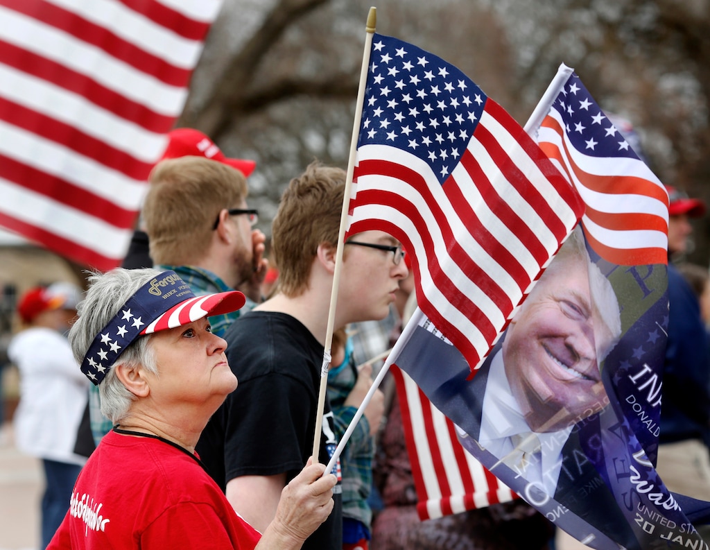 (Jim Beckel | The Oklahoman file photo via AP)  Karen Maples, of Norman, holds an American flag and a Trump inauguration flag at the rally. She wore her "Deplorable Me" shirt and described herself as "American Proud," Many waving American flags and holding hand-made signs expressing pleasure with the new president, supporters of Donald Trump attended a rally Saturday, March 4, 2017, on the south plaza of the state Capitol in Oklahoma City to express their solidarity with him, his administration and his policies.
