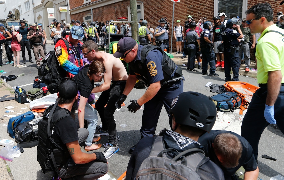 (Steve Helber  |  AP Photo)  Rescue personnel help injured people after a car ran into a large group of protesters after a white nationalist rally in Charlottesville, Va., Saturday, Aug. 12, 2017. The nationalists were holding the rally to protest plans by the city of Charlottesville to remove a statue of Confederate Gen. Robert E. Lee. There were several hundred protesters marching in a long line when the car drove into a group of them.