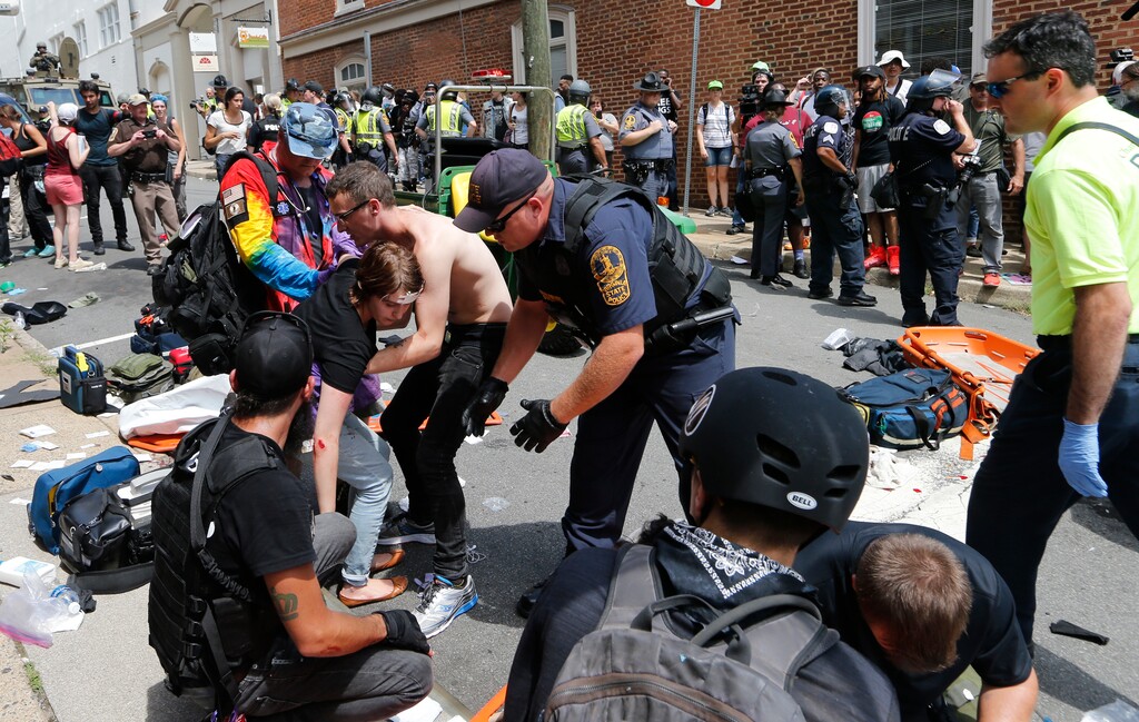 Rescue personnel help injured people after a car ran into a large group of protesters after a white nationalist rally in Charlottesville, Va., Saturday, Aug. 12, 2017. The nationalists were holding the rally to protest plans by the city of Charlottesville to remove a statue of Confederate Gen. Robert E. Lee. There were several hundred protesters marching in a long line when the car drove into a group of them. (AP Photo/Steve Helber)