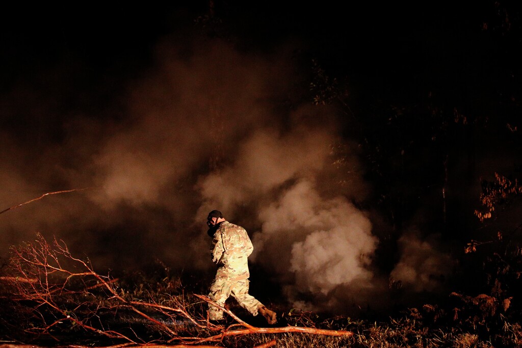Sgt. 1st Class Carl Satterwaite, of the U.S. National Guard, tests air quality near cracks emitting volcanic gases from a lava flow in the Leilani Estates subdivision near Pahoa, Hawaii Thursday, May 10, 2018. Kilauea has destroyed more than 35 structures since it began releasing lava from vents about 25 miles (40 kilometers) east of the summit crater. (AP Photo/Jae C. Hong)