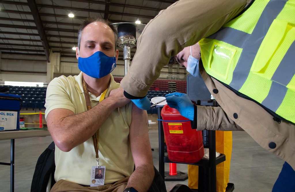 (Francisco Kjolseth | The Salt Lake Tribune) Michael Crookston, Davis High band teacher, is vaccinated by registered nurse Bruno Gonzalez as the Davis County School District begins COVID-19 vaccinations for its teachers at the Davis County Legacy Center in Farmington on Tuesday, Jan. 12, 2021.