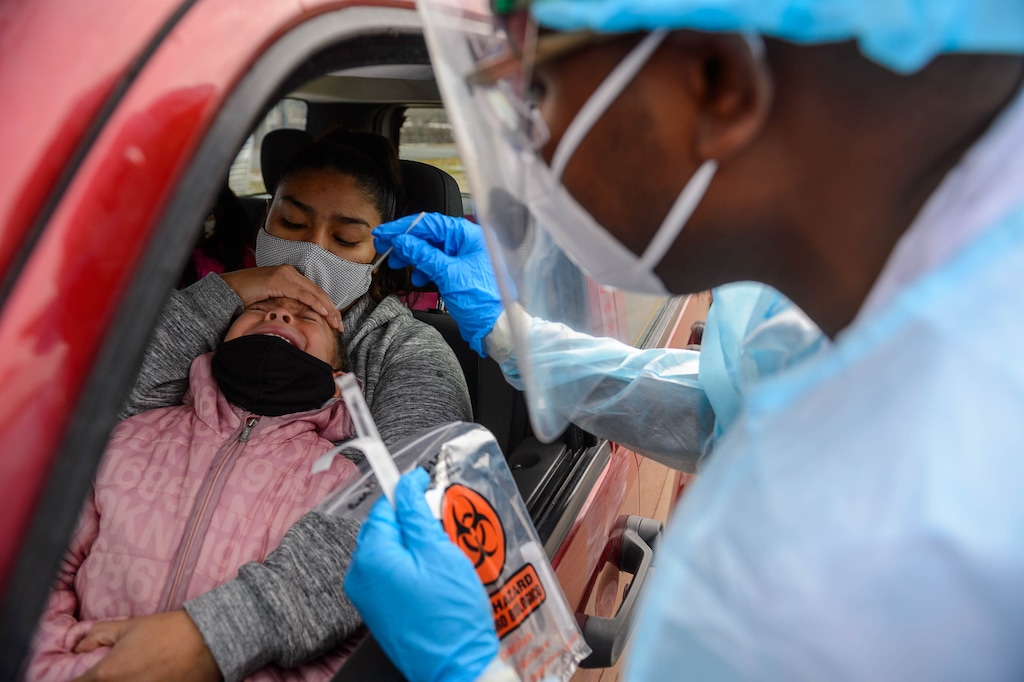 (Trent Nelson  |  The Salt Lake Tribune) Evandro Semedo tests Genisis Magana, in the arms of her mother Carla Miron, at the Utah National Guard’s mobile testing site for COVID-19 in Salt Lake City on Tuesday, Nov. 10, 2020.