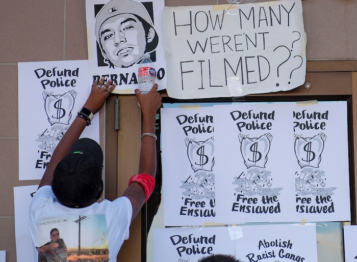 (Leah Hogsten  |  The Salt Lake Tribune) Wearing a t-shirt with a photograph of Zane James, Angela Johnson tapes a flyer of Bernardo Palacios-Carbajal during the People's Council rally to defund the West Valley Police Department outside West Valley City Hall and the police station, Aug.8, 2020.  Saturday's rally was hosted by the Salt Lake chapter of the Party for Socialism and Liberation.