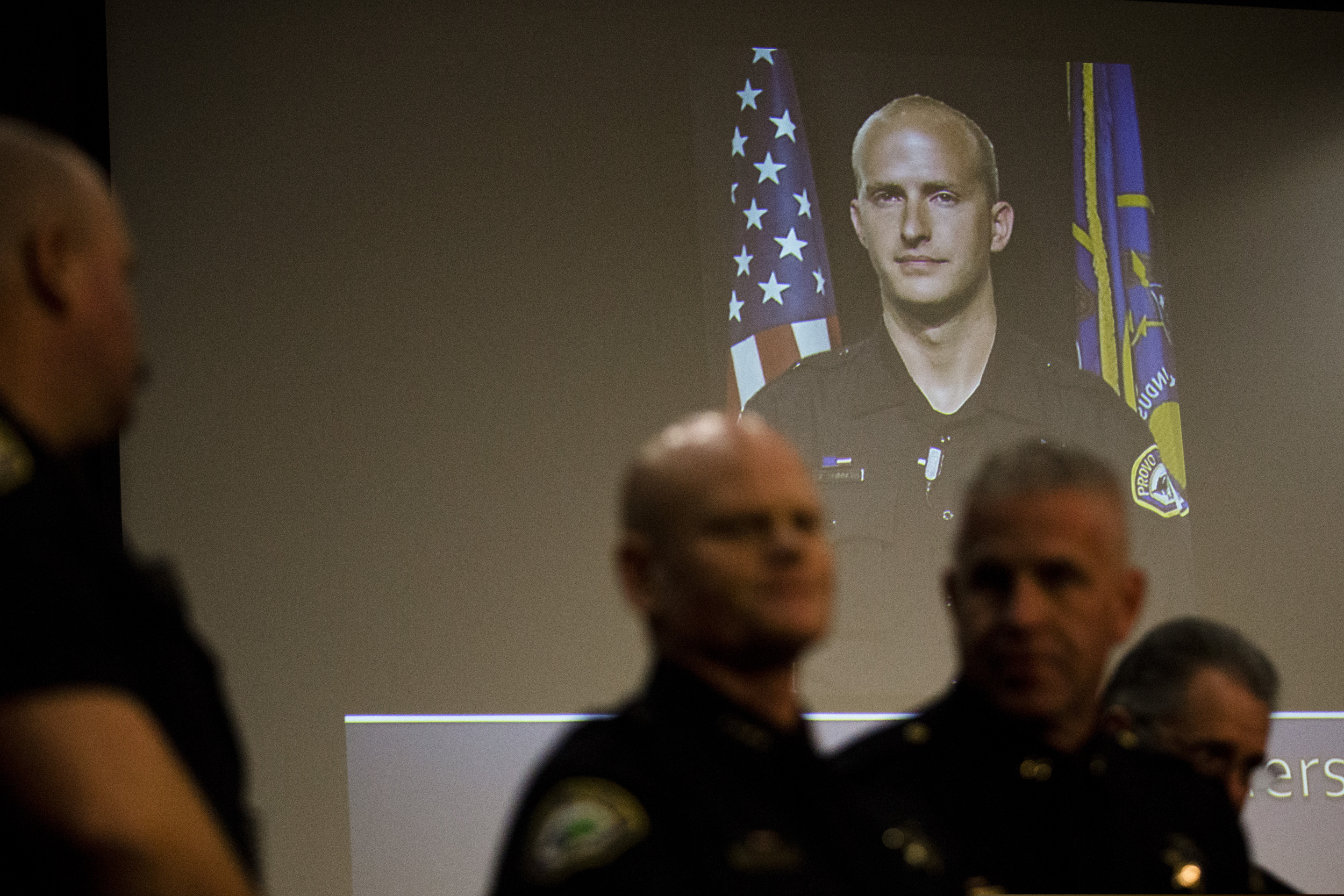 A picture of Joseph Shinners, a Provo police officer who was killed in the line of duty, is projected at the Provo City Center building during a news conference on Sunday, Jan. 6, 2019, in Provo, Utah. Shinners, who was shot and killed while trying to apprehend a fugitive, was a three-year veteran of the force who managed to shoot back and strike the suspect at least once after he was hit by gunfire. (Evan Cobb/The Daily Herald via AP)