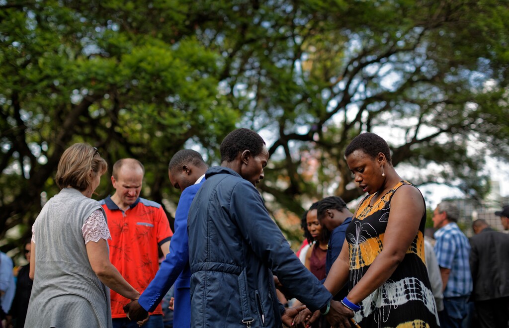 (AP Photo/Ben Curtis) Zimbabweans join hands in prayer at a Christian peace and prayer rally in downtown Harare, Zimbabwe Sunday, Nov. 19, 2017.
