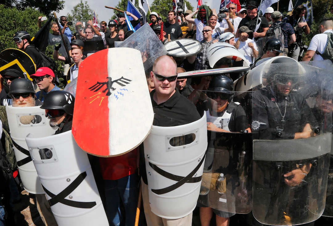 (Steve Helber  |  AP Photo)  White nationalist demonstrators use shields as they guard the entrance to Lee Park in Charlottesville, Va., Saturday, Aug. 12, 2017.