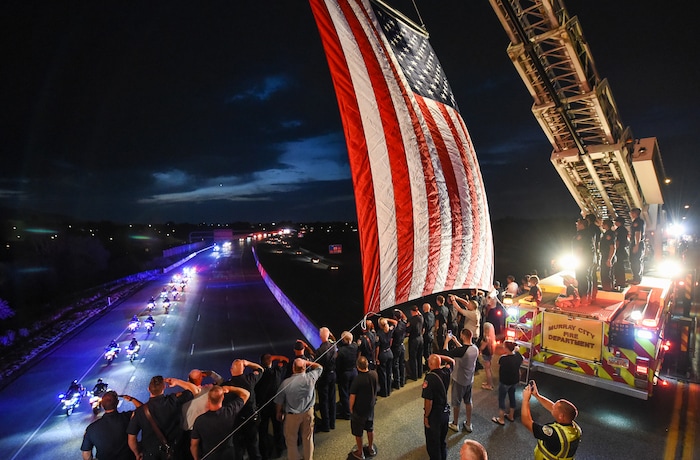 (Francisco Kjolseth  |  The Salt Lake Tribune)  The body of Utah firefighter Matt Burchett, 42, who died fighting a wildfire in California is honored by a firefighter detail along Murray Parkway as his body is returned home, traveling along I-215 after being flown in to the Utah Air National Guard in Salt Lake City on Wed. Aug. 15, 2018. The remains of the Draper battalion chief were transported to Jenkins-Soffe Mortuary in South Jordan.