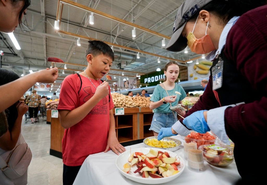 (Bethany Baker  |  The Salt Lake Tribune) H Mart employee Sue Jarrett, at right, prepares samples for customers during the grand opening of H Mart, the newest store in a Asian grocery store chain, in West Jordan on Friday, June 7, 2024.