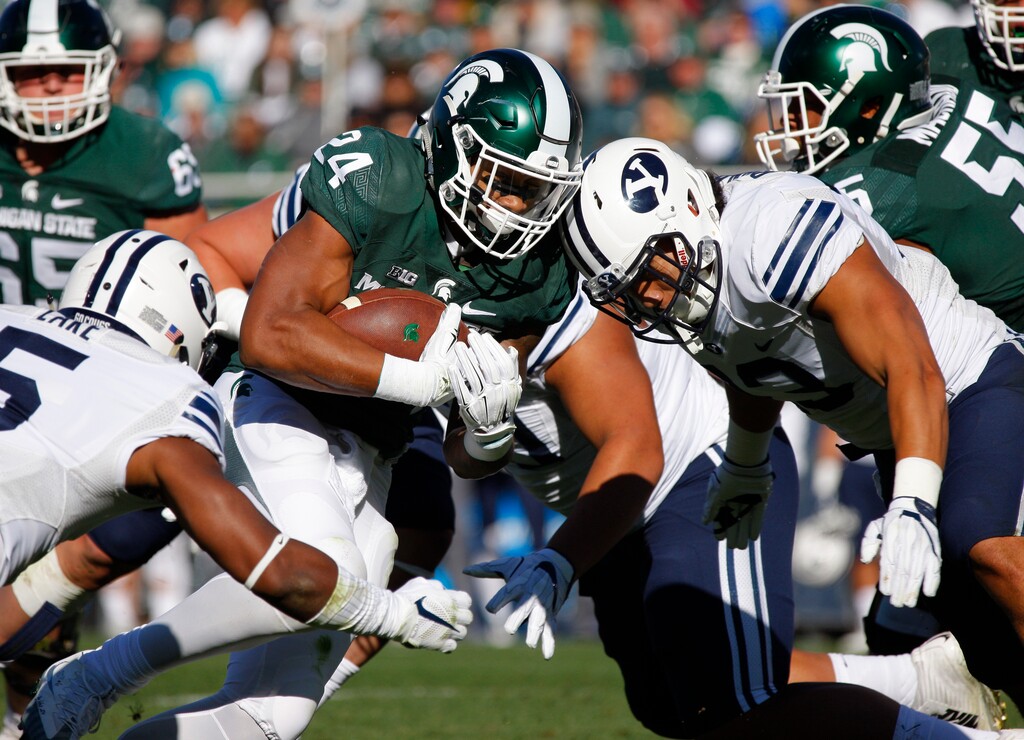 Michigan State's Gerald Holmes (24) rushes against BYU's Dayan Lake, left, and Francis Bernard, right, during the first quarter of an NCAA college football game, Saturday, Oct. 8, 2016, in East Lansing, Mich. (AP Photo/Al Goldis)