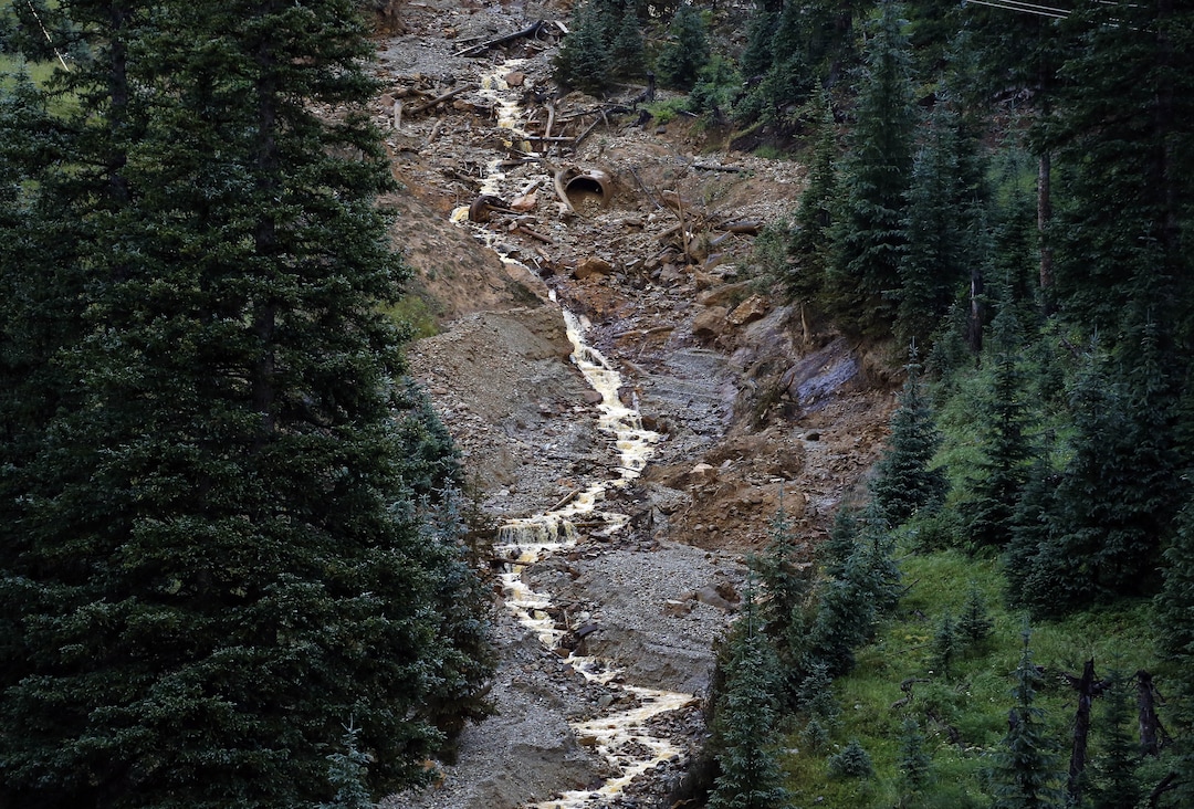 Water flows down from the Gold King mine, where several days earlier an accident led to the release of heavy metals and chemical-laden wastewater, outside Silverton, Colo., Wednesday, Aug. 12, 2015. The Environmental Protection Agency has taken full responsibility for the mine waste spoiling rivers downstream from Silverton, but people who live near the idled and leaking Gold King mine say local authorities and mining companies spent decades spurning federal cleanup help. (AP Photo/Brennan Linsley)
