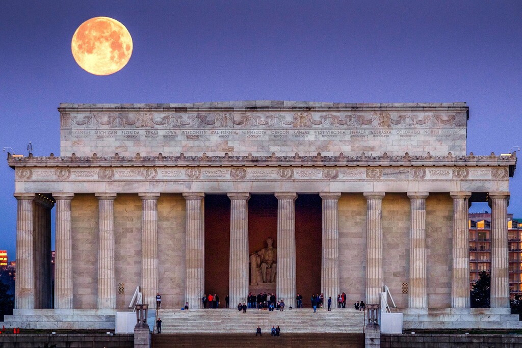 (J. David Ake | AP) The full moon sets behind the Lincoln Memorial as people line the steps to watch the sun come up across the other end of the National Mall in Washington, Saturday, March 31, 2018.