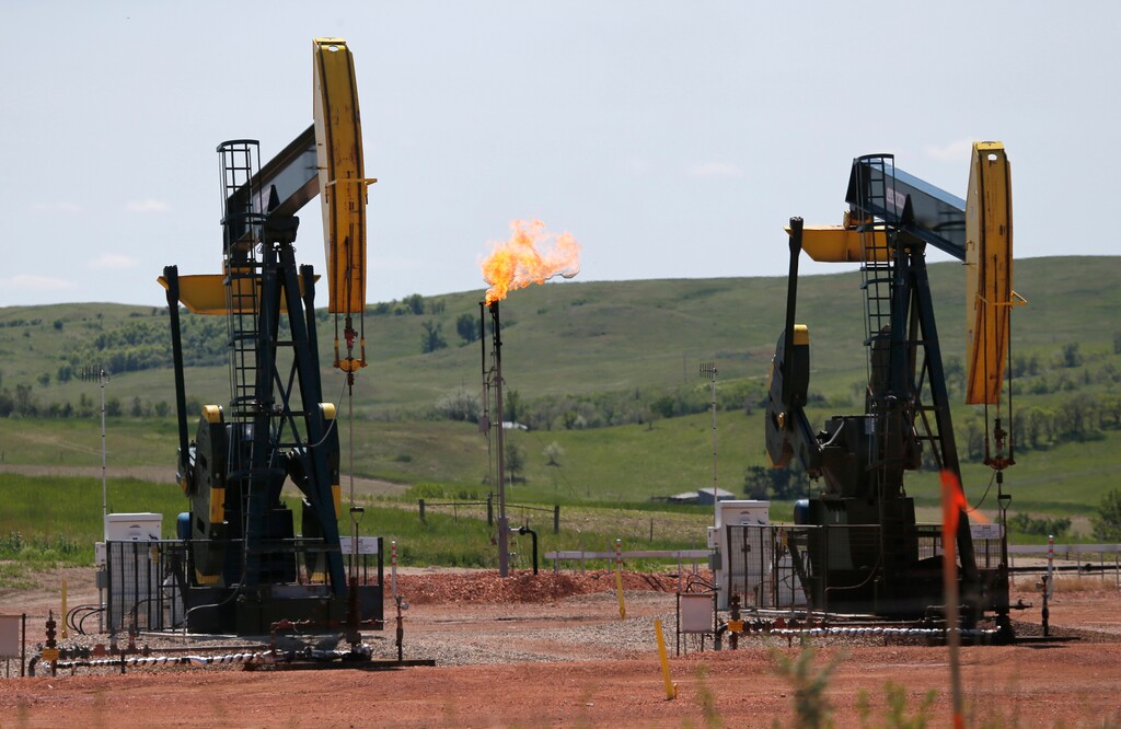 (Charles Rex Arbogast | The Associated Press) In this June 12, 2014, file photo, oil pumps and natural gas burn off in Watford City, N.D. The Interior Department is delaying an Obama-era regulation aimed at restricting harmful methane emissions from oil and gas production on federal lands. A rule being published Dec. 8, delays the methane regulation until January 2019, calling the previous rule overly burdensome to industry.