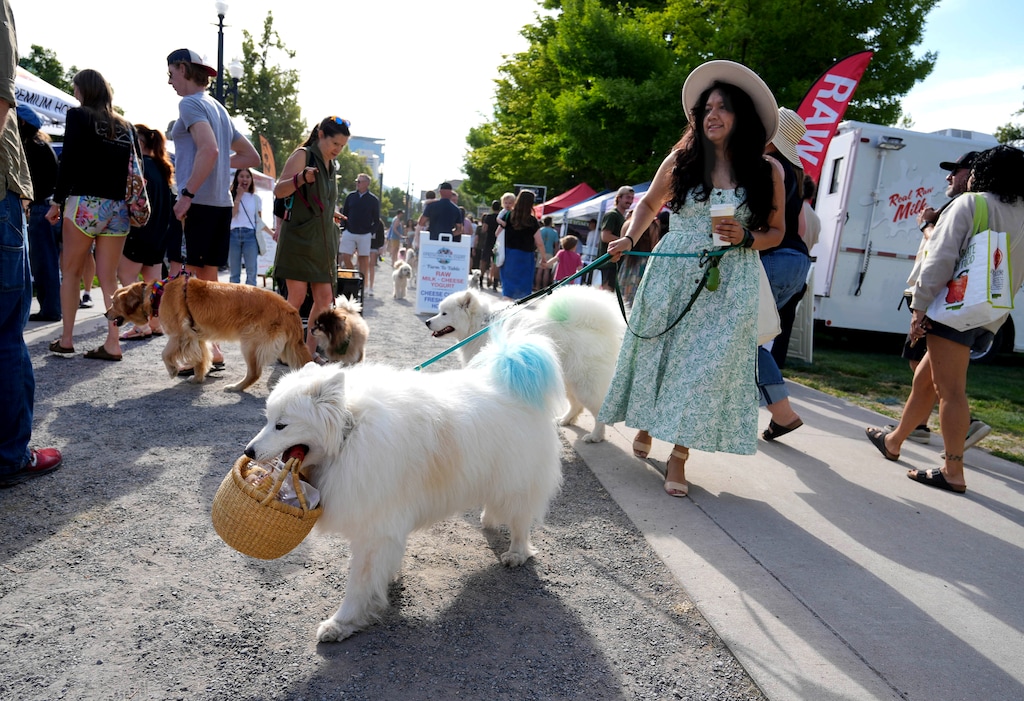 (Francisco Kjolseth | The Salt Lake Tribune) Maite Carranza is assisted with her shopping by her dogs Nimbus and Stratus as people enjoy the Downtown Farmer's Market in Salt Lake City on Saturday, June 7, 2025. A new building is being proposed at the park, designed to house portions of the market and activate the urban park year-round.