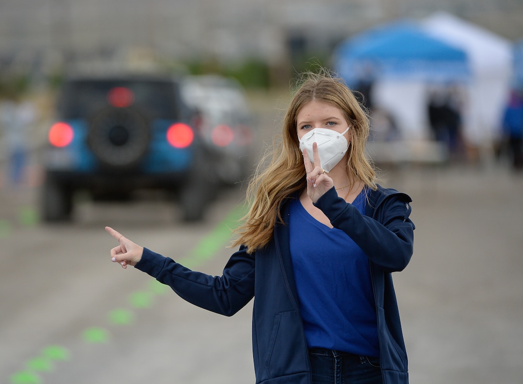 (Francisco Kjolseth  |  The Salt Lake Tribune) Emma Epperson directs traffic to different lanes as people line up in their cars for COVID-19 antibody testing at the Galena Hills Park in Draper on Wednesday, May 20, 2020.