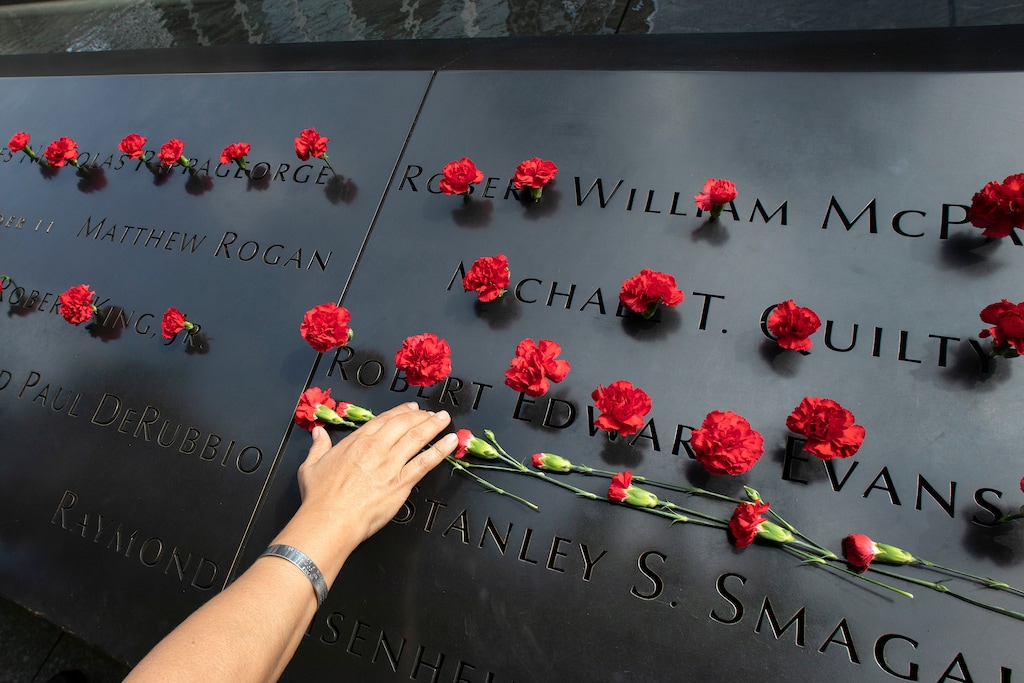 (Mark Lennihan | AP Photo) Norma Molina, of San Antonio, Texas, leaves flowers by the names of firefighters from Engine 33 at the September 11 Memorial, Monday, Sept. 9, 2019, in New York. Her boyfriend Robert Edward Evans, a member of Engine 33, was killed in the north tower of the World Trade Center on Sept. 11, 2001.