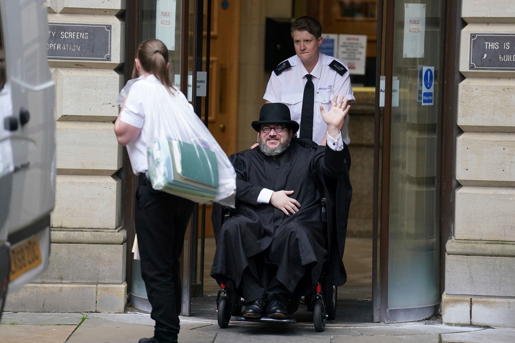 (Andrew Milligan | PA via AP) Nicholas Rossi from the U.S. waves as he leaves the Edinburgh Sheriff and Justice of the Peace Court in Edinburgh, Scotland, Wednesday, July 12, 2023. An American fugitive accused of faking his own death to avoid a rape charge has been ordered by a judge in Scotland to be returned to the U.S.