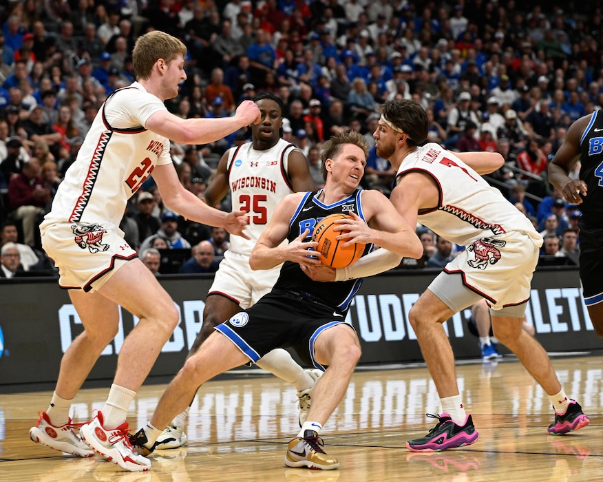Brigham Young guard Dawson Baker, front center, struggles to control the ball as, from left, Wisconsin forward Steven Crowl, guard John Blackwell and forward Carter Gilmore defend during the first half in the second round of the NCAA college basketball tournament Saturday, March 22, 2025, in Denver. (AP Photo/John Leyba)