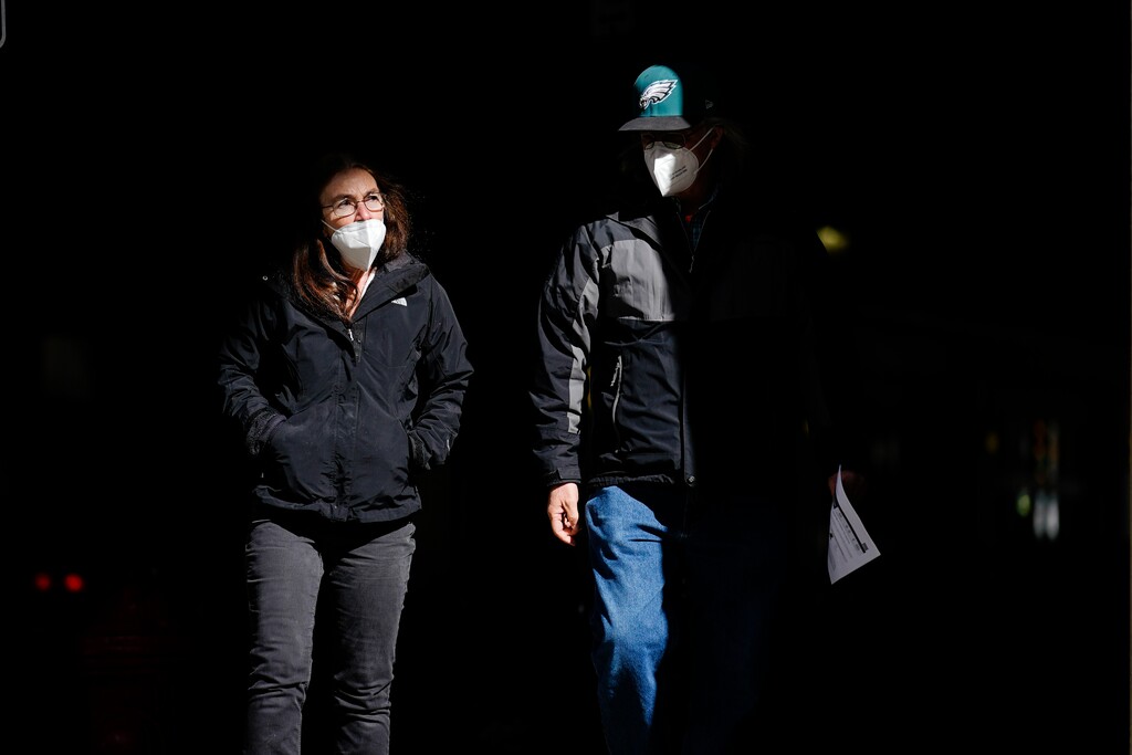(Matt Rourke | AP Photo )In this Wednesday, March 3, 2021 photo, people wearing face masks as a precaution against the coronavirus walk through a shaft of light on a street in Philadelphia. On Tuesday, April 27, 2021, U.S. health officials say fully vaccinated Americans don't need to wear masks outdoors anymore unless they are in a big crowd of strangers, and those who are unvaccinated can go without a face covering outside in some cases, too.
