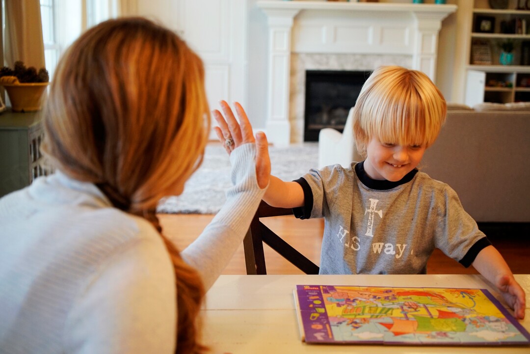 In this Wednesday, March 27, 2019, photo, Kacey Ruegsegger Johnson high-fives with her son Corban as they finish a puzzle in their Cary, N.C., home. Twenty years after teenage gunmen attacked Columbine High School, Ruegsegger Johnson and other alumni of the Littleton, Colo., school have become parents. “I'm grateful I have the chance to be a mom. I know some of my classmates weren't given that opportunity,” Ruegsegger Johnson said, tears springing to her eyes. (AP Photo/Allen G. Breed)