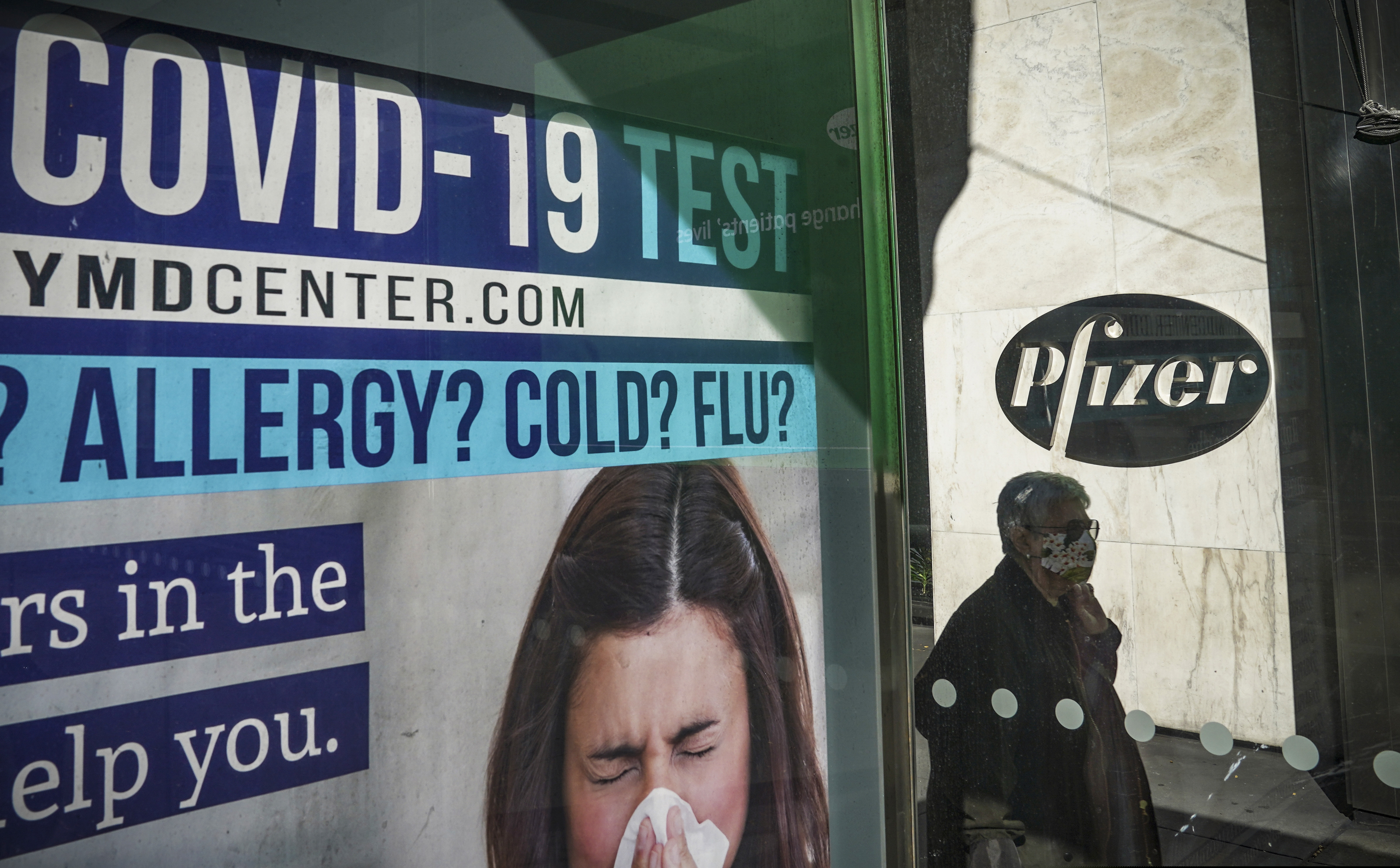 (Bebeto Matthews | The Associated Press) A bus stop ad for COVID-19 testing is shown outside Pfizer world headquarters in New York on Monday Nov. 9, 2020. Pfizer says an early peek at its vaccine data suggests the shots may be 90% effective at preventing COVID-19, but it doesn't mean a vaccine is imminent.