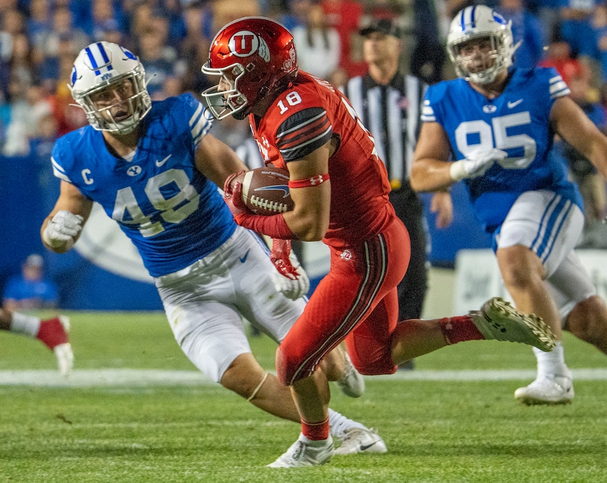 (Rick Egan | The Salt Lake Tribune) Utah Utes wide receiver Britain Covey (18) returns a punt as Brigham Young Cougars linebacker Payton Wilgar (49) and Brigham Young Cougars defensive lineman Caden Haws (95) defend, in football action between the Utah Utes and the Brigham Young Cougars at Lavell Edwards Stadium in Provo, on Saturday, Sept. 11, 2021.