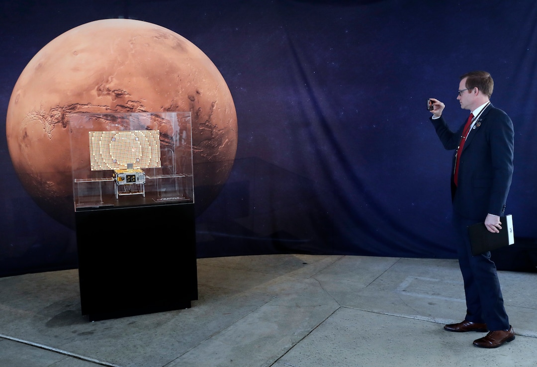 (Marcio Jose Sanchez | The Associated Press) A man takes pictures of a model of the CubeSat MarCO which trails the InSight lander on its mission to Mars at NASA's Jet Propulsion Laboratory Monday, Nov. 26, 2018, in Pasadena, Calif. The technology onboard each CubeSat will provide NASA the ability to quickly transmit status information about InSight as it lands on Mars. A NASA spacecraft is just a few hours away from landing on Mars. The InSight lander is aiming for a Monday afternoon touchdown on what scientists and engineers hope will be a flat plain on the red planet.
