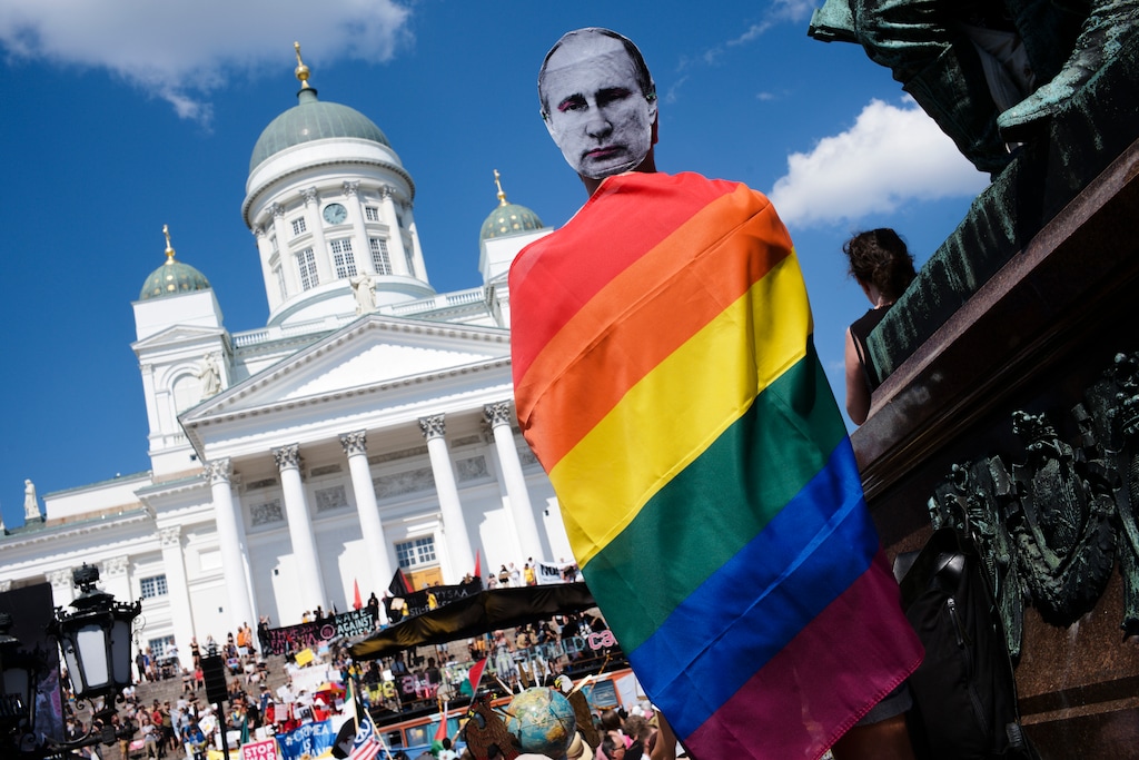 A man with a Putin mask and a rainbow flag attends a rally against the policy of U.S. President Donald Trump and Russian President Vladimir Putin in central Helsinki, Sunday, July 15, 2018. President Trump and President Putin will meet in Finland's capital on Monday, July 16, 2018. (AP Photo/Markus Schreiber)