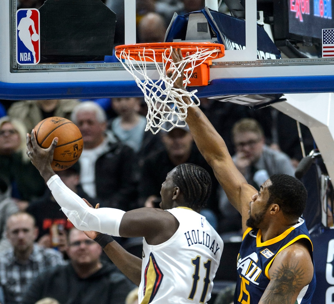 (Steve Griffin  |  The Salt Lake Tribune) Utah Jazz forward Derrick Favors (15) gets his his hand stuck in the net as New Orleans Pelicans guard Jrue Holiday (11) gets past him during the the Utah Jazz versus the New Orleans Pelicans NBA basketball game at the Vivint Smart Home Arena in Salt Lake City Wednesday January 3, 2018.