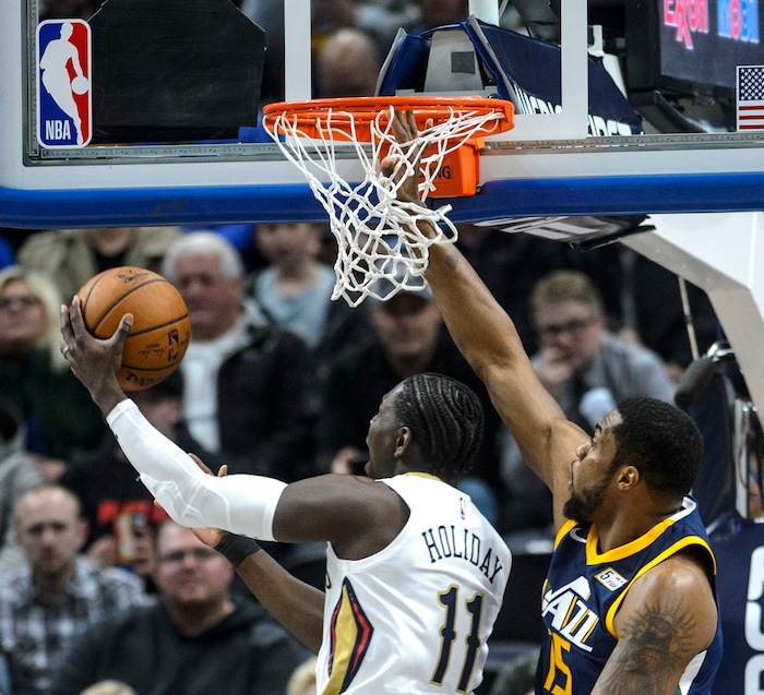 (Steve Griffin  |  The Salt Lake Tribune) Utah Jazz forward Derrick Favors (15) gets his his hand stuck in the net as New Orleans Pelicans guard Jrue Holiday (11) gets past him during the the Utah Jazz versus the New Orleans Pelicans NBA basketball game at the Vivint Smart Home Arena in Salt Lake City Wednesday January 3, 2018.