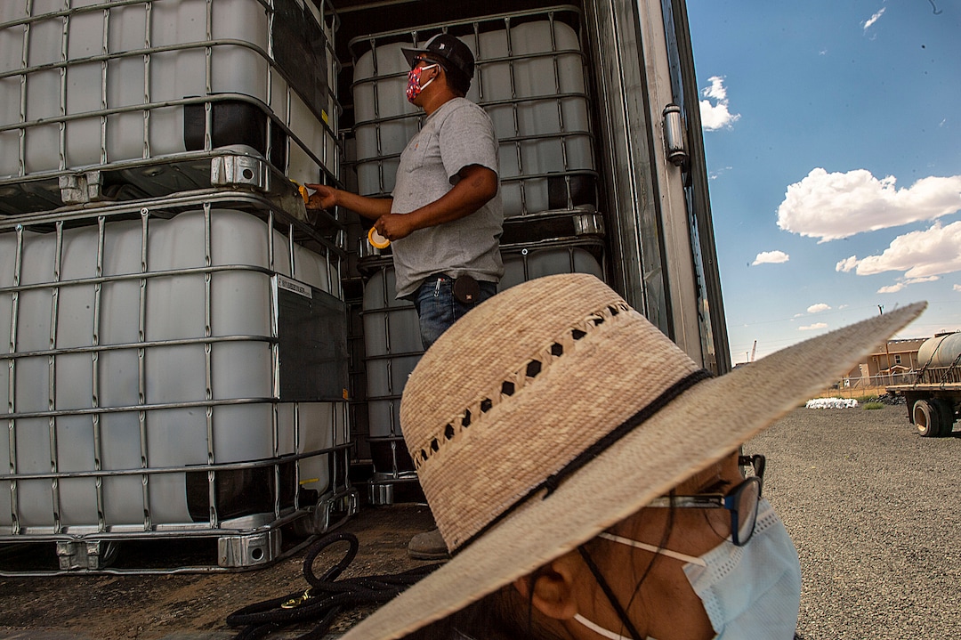 (Leah Hogsten  |  The Salt Lake Tribune) Latimer Sherman, a solar and water technician on the Navajo Water Project for DigDeep and project manager Shanna Yazzie unload 60 250-gallon water tanks in Dilkon, Arizona, June 23, 2020. Sherman and Yazzie distributed a portion of the water tanks to residents in San Juan County a week later.