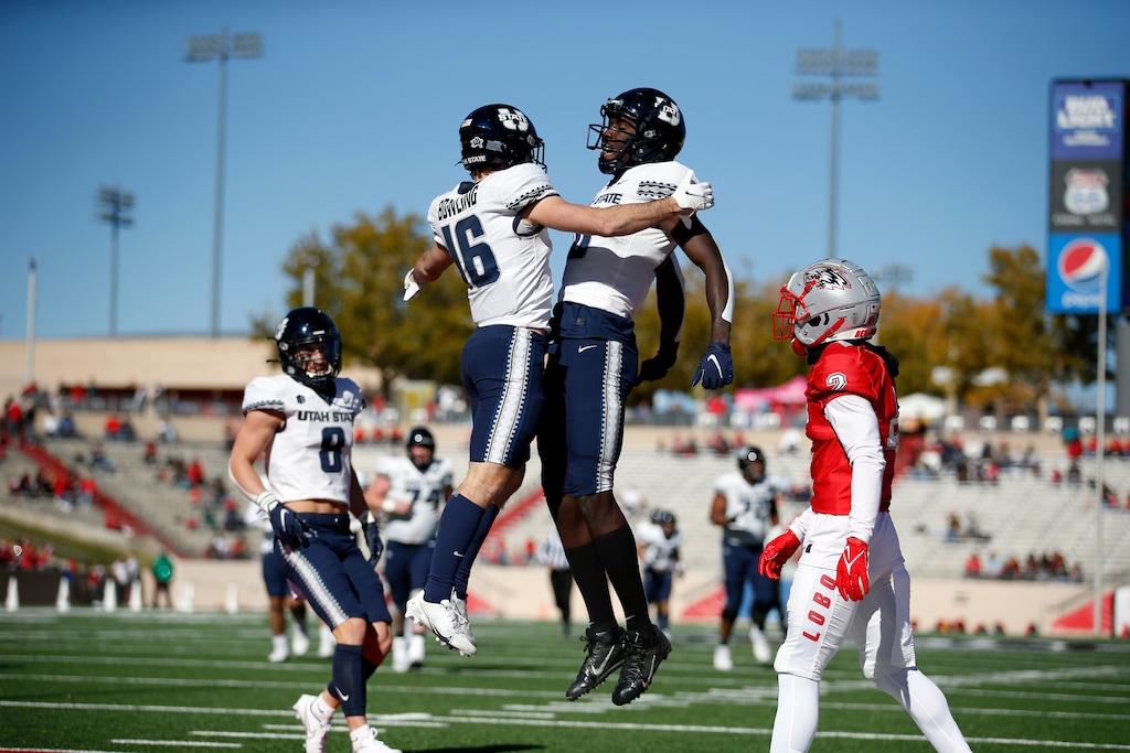 (Andres Leighton | AP) Utah State wide receiver Brandon Bowling (16) celebrates with teammate Justin McGriff (10) after scoring a touchdown against New Mexico during the first half of an NCAA college football game on Friday, Nov. 26, 2021, in Albuquerque, N.M.