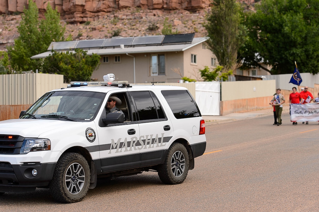 Trent Nelson | The Salt Lake Tribune
With a wall-off compound in the background, a Colorado City Marshal vehicle leads the way as the Colorado City and Hildale Fourth of July Parade makes its way down Central Street in Hildale, UT, and Colorado City, AZ, Saturday July 2, 2016.