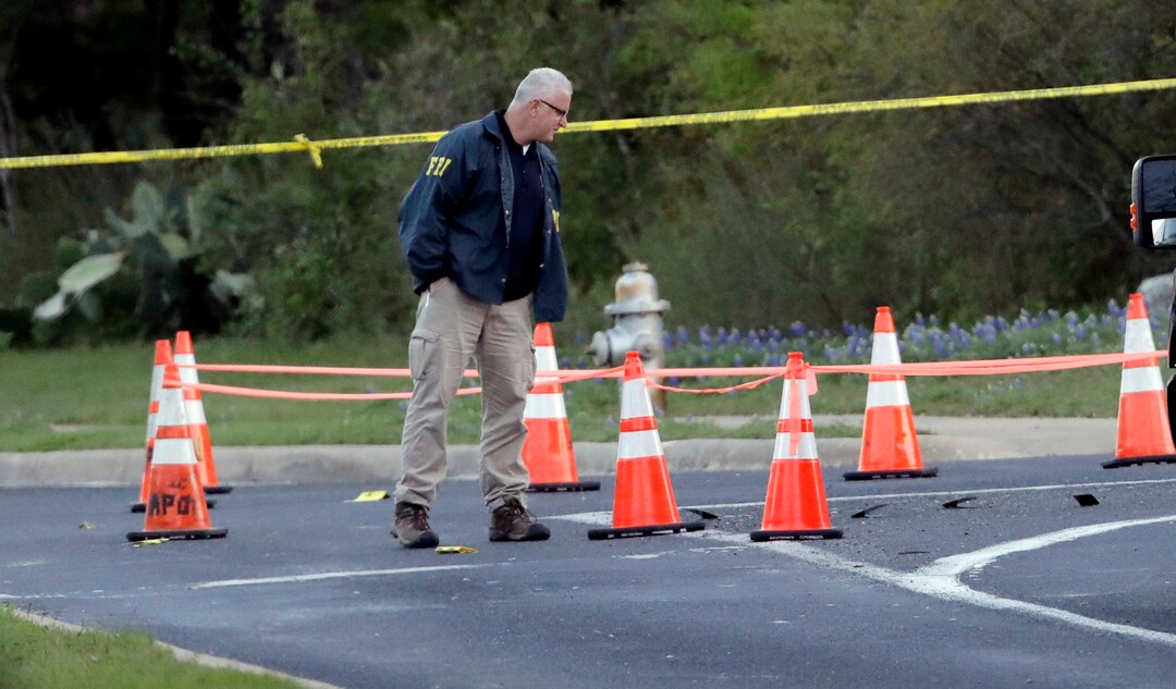 Officials work near the site of Sunday's deadly explosion, Monday, March 19, 2018, in Austin, Texas. Police warned nearby residents to remain indoors overnight as investigators looked for possible links to other package bombings elsewhere in the city this month. (AP Photo/Eric Gay)
