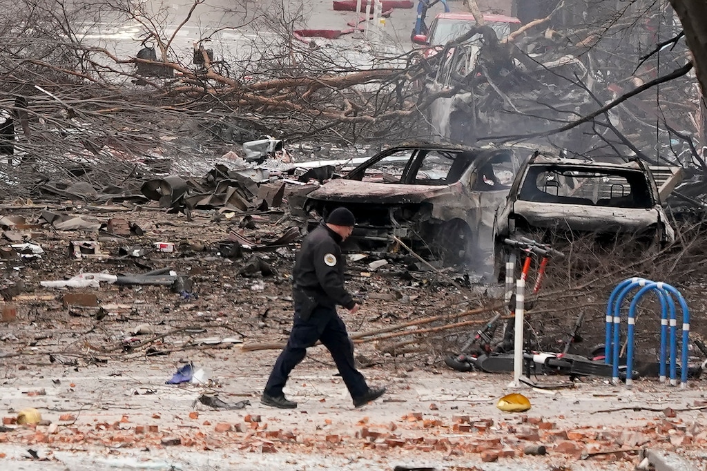 (Mark Humphrey | AP) A law enforcement member walks past damage from an explosion in downtown Nashville, Tenn., Friday, Dec. 25, 2020. Buildings shook in the immediate area and beyond after a loud boom was heard early Christmas morning.