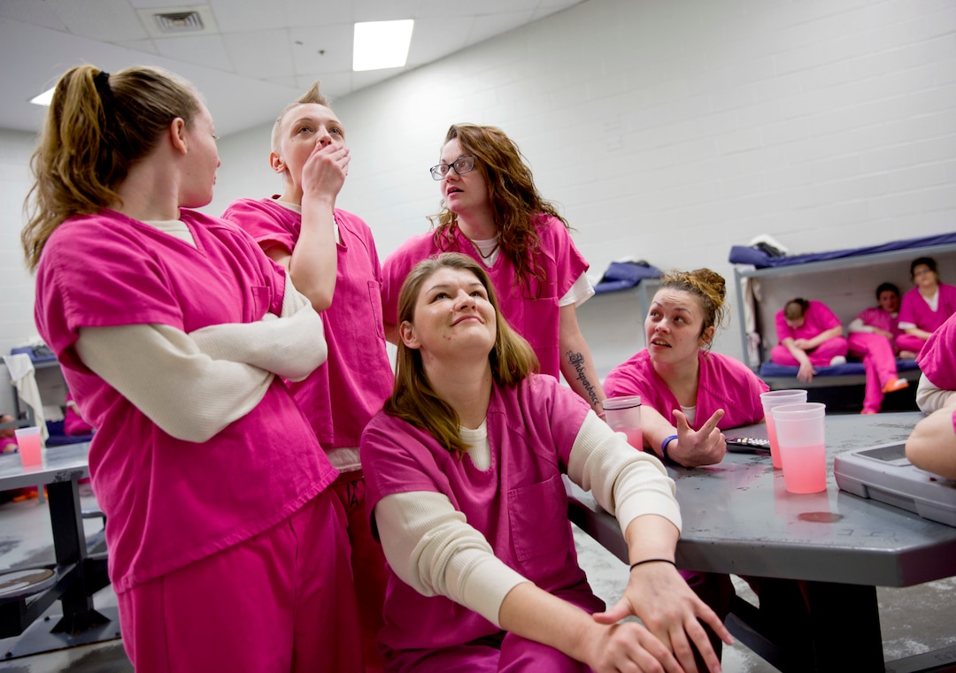 Inmate Tara White, 28, second from left, reacts to hearing her cousin was arrested as she watches the local news in her cell at the Campbell County Jail in Jacksboro, Tenn., Tuesday, March 20, 2018. Every evening around dinnertime, inmates gather around a small television mounted high on the wall to listen to the police log and obituary notices. It's often the main source for inmates to find out if anyone they know has been arrested or died from an overdose. (AP Photo/David Goldman)