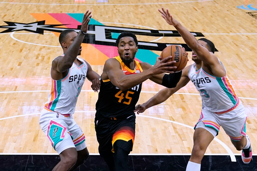 Utah Jazz guard Donovan Mitchell (45) drives to the basket between San Antonio Spurs guard Lonnie Walker IV (1) and forward Keldon Johnson (3) during the second half of an NBA basketball game Friday, March 11, 2022, in San Antonio. (AP Photo/Eric Gay)