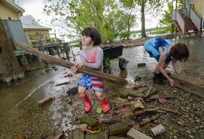(Matthew Hinton | AP Photo) Delilah Campbell, 4, left, and her sister, Tallulah Campbell, 8, clear out driftwood and other debris in preparation of Tropical Storm Barry near New Orleans, La., Thursday, July 11, 2019. The area is normally a driveway at her family's home that is one of the few on land called batture on the outside of the Mississippi River levee at the border of Orleans and Jefferson Parishes.