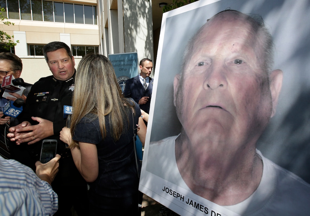 (Rich Pedroncelli | The Associated Press) Sacramento County Sheriff Scott Jones, left, talks to reporters about the arrest Joesph James DeAngelo, seen in photo, on suspicion of committing a string of violent crimes in the 1970's and 1980's after a news conference. Wednesday, April 25, 2018, in Sacramento, Calif. A DNA match led to the arrest of DeAngelo, 72, Tuesday. DeAngelo is believed to have committed at least 12 slayings and 45 rapes in California.