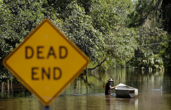 A man, who refused to be identified, pushes a canoe through water from the Alafia River Tuesday, Sept. 12, 2017, in Lithia, Fla. A storm surge from Hurricane Irma pushed water into the low lying area. (AP Photo/Chris O'Meara)