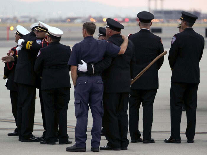 (Steve Griffin  |  Deseret News, pool photo)  Members of the Draper City Fire Department and Unified Fire Authority Honor Guard stand with family members after the casket of Draper Battalion Chief Matt Burchett is placed in a hearse after being transported from California to Utah in a C130-J by the California Air National Guard. The C130-J landed at the Utah Air National Guard Base in Salt Lake City on Wednesday, Aug. 15, 2018. Burchett was killed while fighting the Mendocino Complex Fire north of San Francisco.